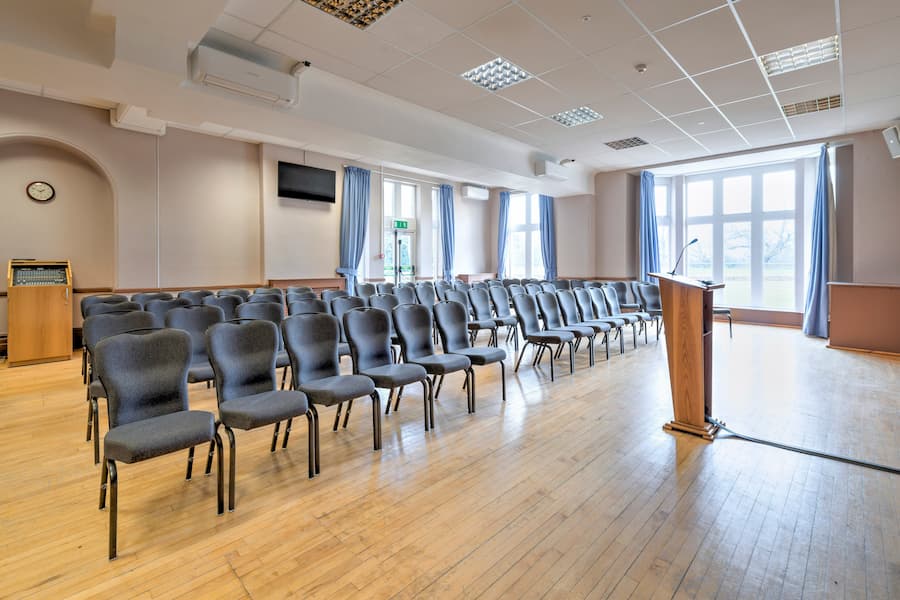 A view of Barclay Hall from the front looking at the chairs set in theatre style with light streaming through the windows.