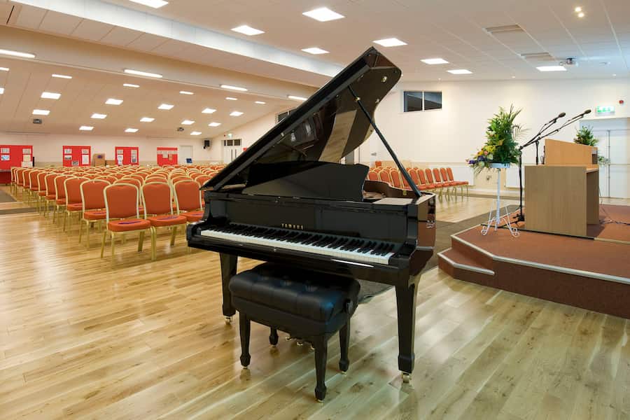The Butterley Hall looking from the front out to the audience with a view of the grand piano and the many chairs.