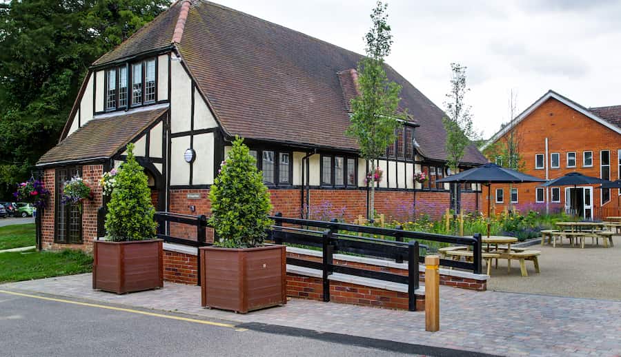 The exterior of the Chapel Barn with grey skies and 2 large potted trees in front.