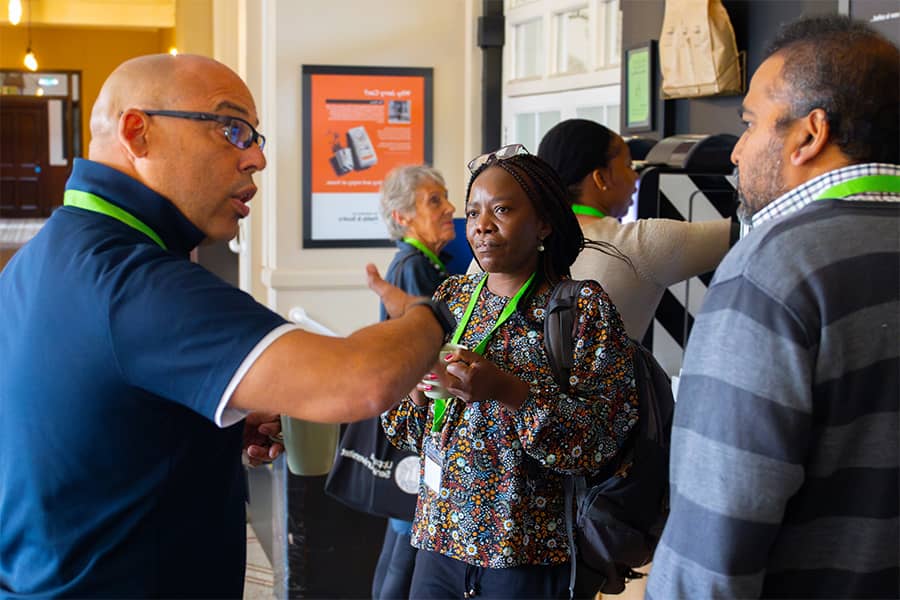 Two men and one woman chatting through their conference theme over a cup of coffee in the coffee area at High Leigh