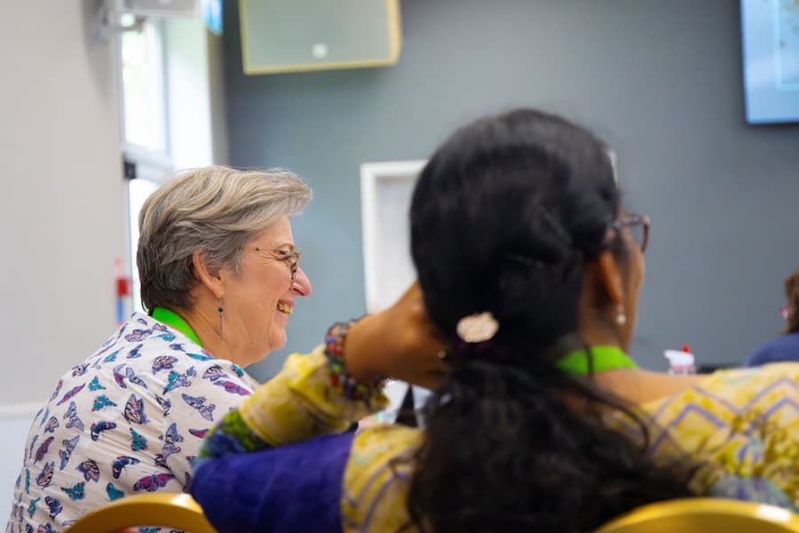 A elderly woman in an audience laughing in the Yew Tree Hall at High Leigh.