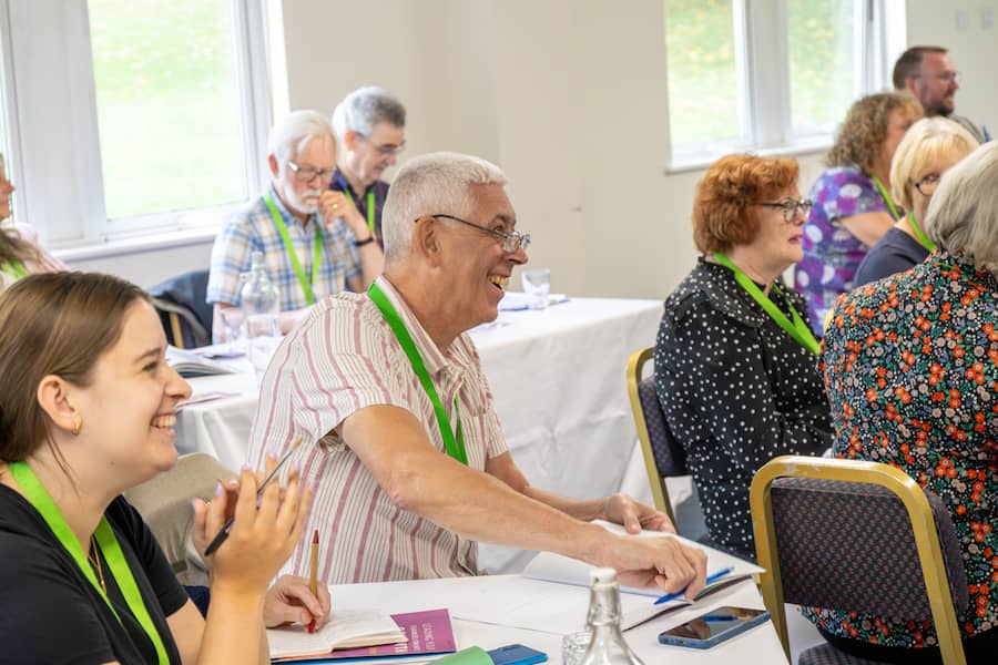 A man in a white and pink shirt laughing at the Leading Your Church Into Growth conference.
