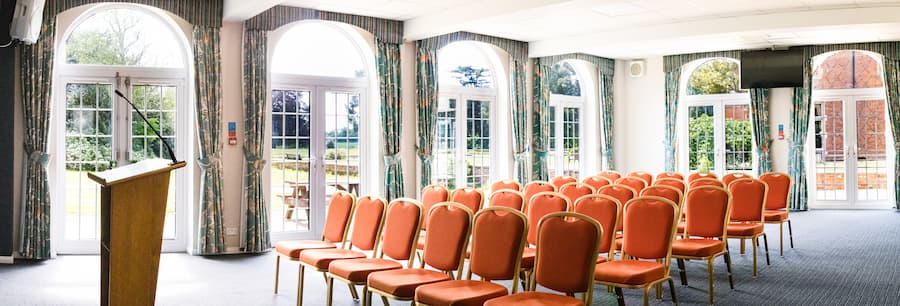 Willow room with sunlight streaming through the windows, set in a theatre set up with orange chairs.