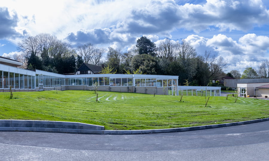 The orchard at The Hayes with green grass and a partially cloudy sky.