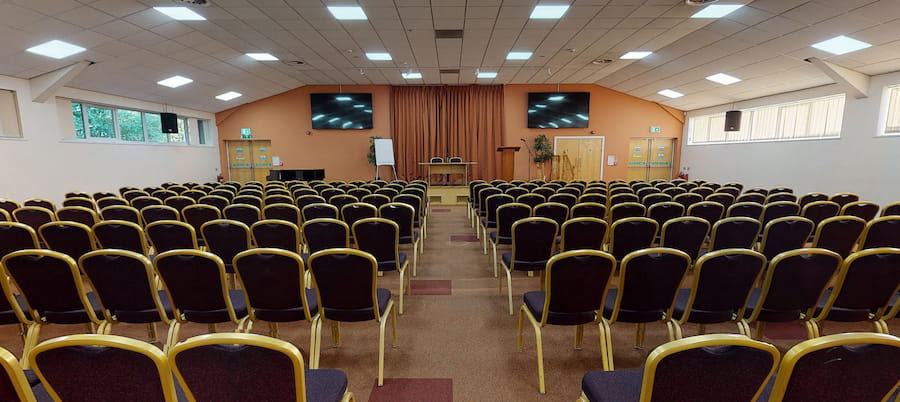 The Derbyshire Hall set as theatre layout with an orange outdated colour scheme and old carpet before the renovations.