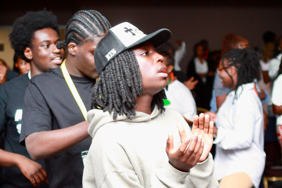 A youth member clapping during a worship session.