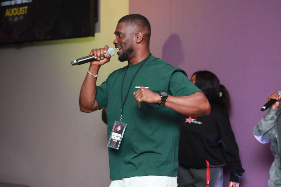 A man on stage in the Derbyshire Hall with a microphone singing and dancing.