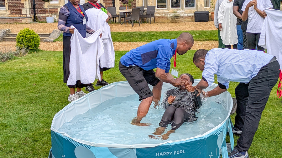 2 men baptising a young woman outside High Leigh.