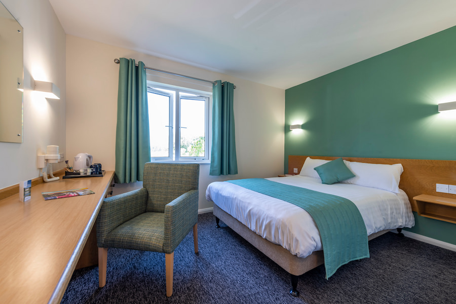 A double room at The Hayes showing the bed, the window and the desk with coffee and tea making facilities. 