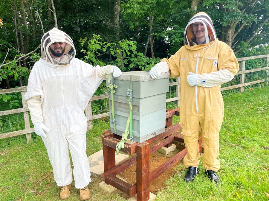 2 members of Highgate House staff in bee protective gear setting up the hive. 