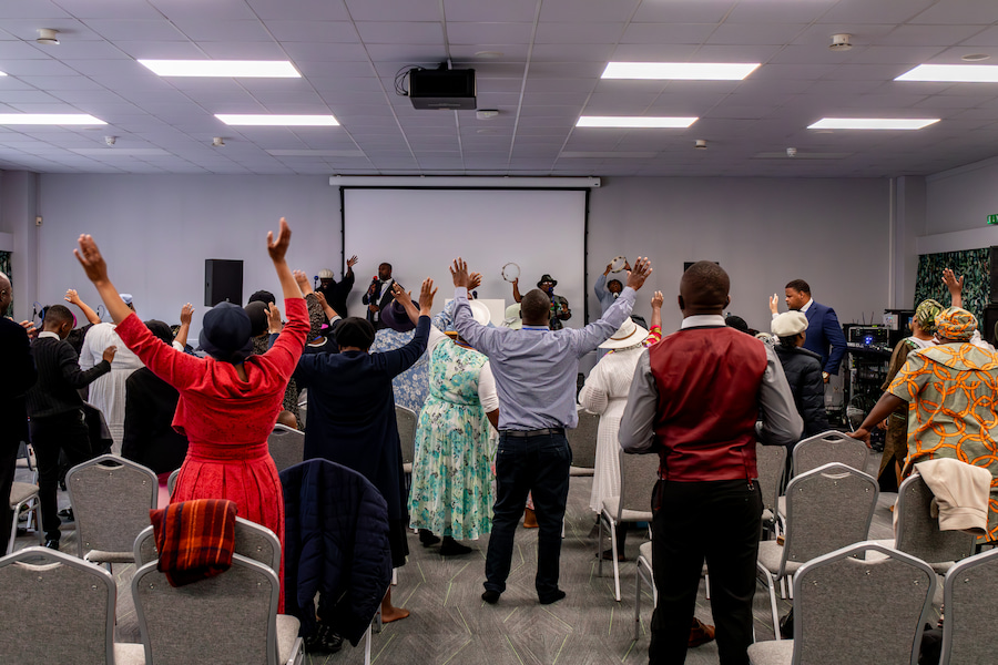 Guests in the Aspen hall at Highgate House worshipping with their hands up.