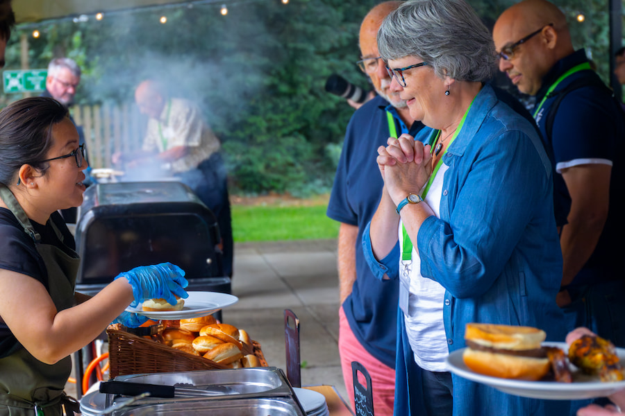 A staff member serving a guest during a lunch time BBQ.