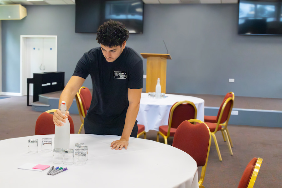 A young staff member putting water out on the tables ready for a conference.
